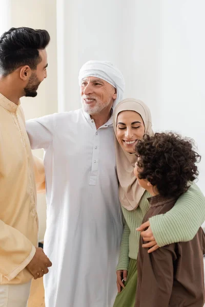 Interrassische muslimische Familie umarmt sich, während sie sich zu Hause anschaut — Stockfoto