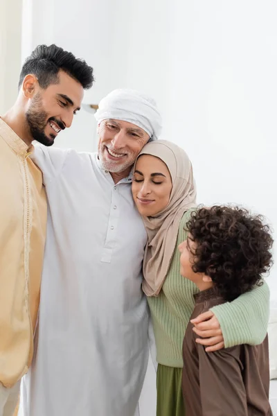 Весёлая многонациональная мусульманская семья, обнимающая дома — стоковое фото