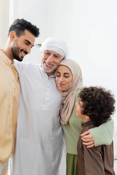 Alegre familia multiétnica musulmana abrazando en casa — Stock Photo