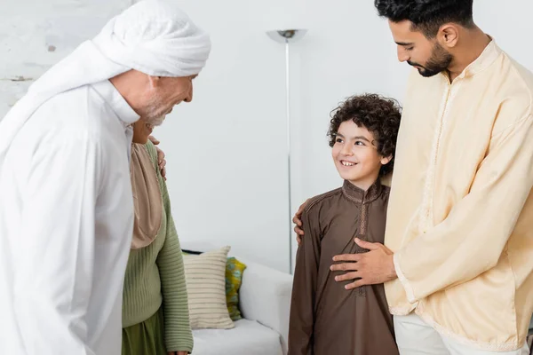 Älterer muslimischer Mann umarmt Tochter, während er den arabischen Enkel zu Hause ansieht — Stockfoto