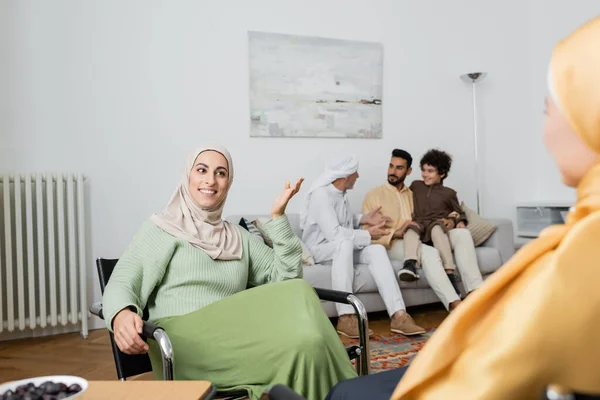 Femme musulmane heureuse parlant à la mère près de la famille multiethnique dans le salon — Photo de stock