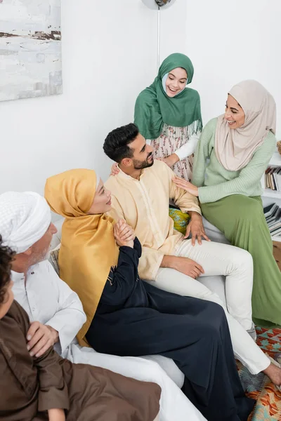 Високий кут зору арабської жінки, що сміється біля чоловіка та багатоетнічної сім'ї вдома — стокове фото