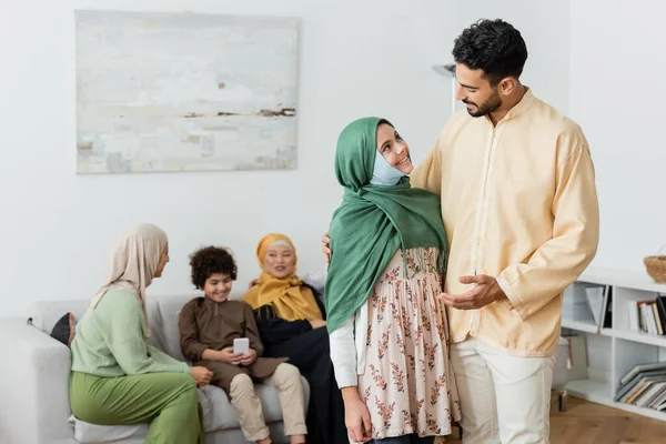 Arabian man talking to muslim daughter near multiethnic family on blurred background — Stock Photo