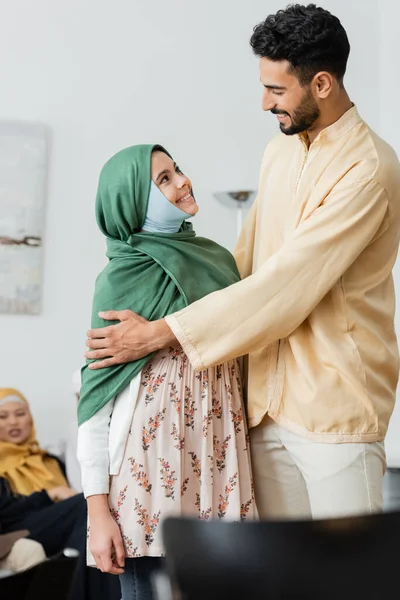 Счастливый арабский мужчина обнимает мусульманскую дочь в хиджабе дома — стоковое фото