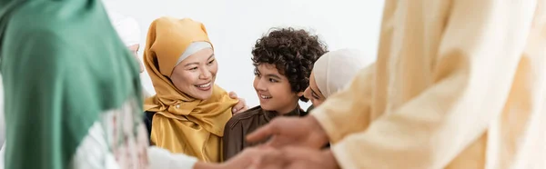Blurred man holding hands with daughter near interracial muslim family, banner — Stock Photo
