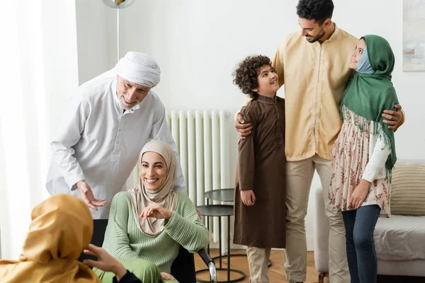 Árabe hombre abrazando interracial niños cerca musulmán familia en casa - foto de stock