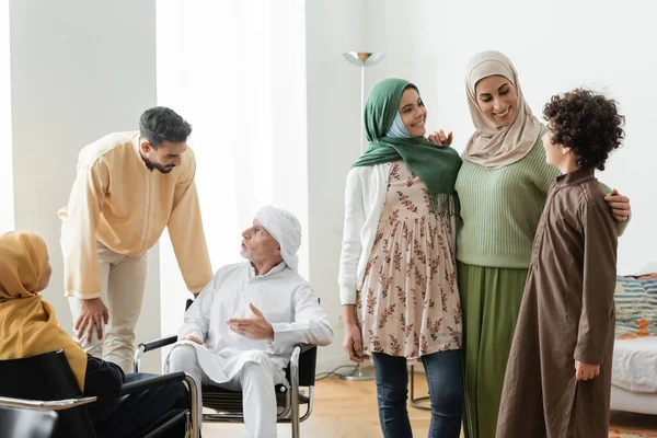 Mature man talking to adult son near multiethnic muslim family at home — Stock Photo