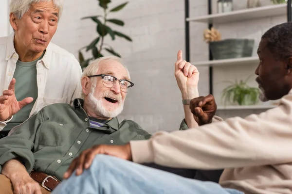 Des hommes interraciaux positifs parlent à un ami afro-américain à la maison — Photo de stock