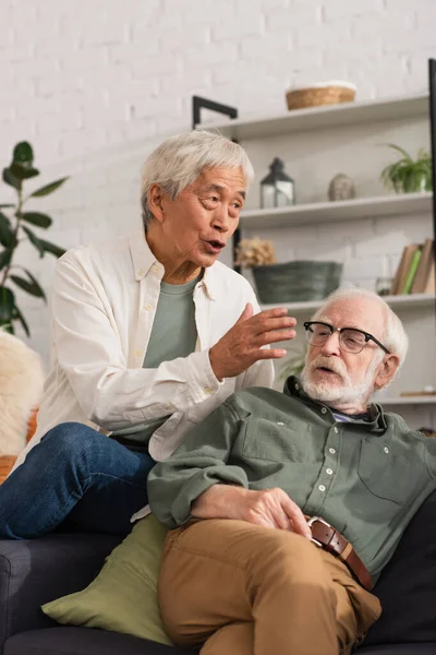 Літній азіатський чоловік розмовляє біля друга на дивані вдома — стокове фото