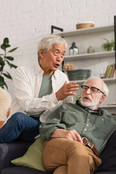 Âgé asiatique l'homme parler près ami sur canapé à la maison — Photo de stock