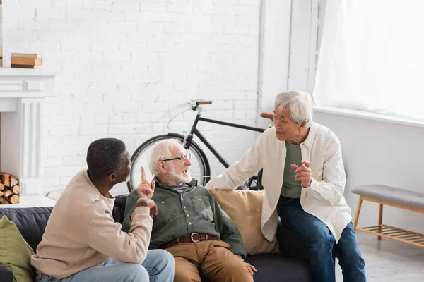 Hombre mayor que tiene idea cerca de amigos multiétnicos en casa — Stock Photo