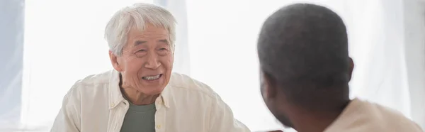 Positivo asiatico uomo guardando africano americano amico a casa, striscione — Foto stock