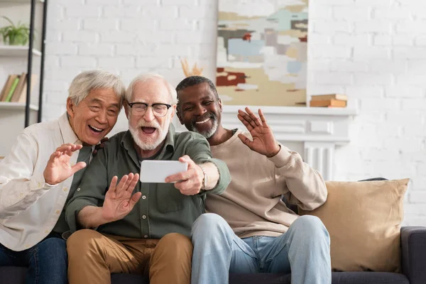 Amis multiethniques âgés ayant un appel vidéo sur téléphone portable à la maison — Photo de stock