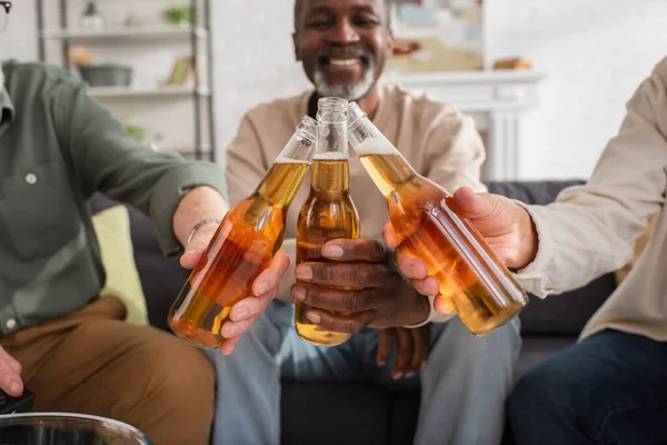 Blurred interracial amis clinking bière à la maison — Photo de stock
