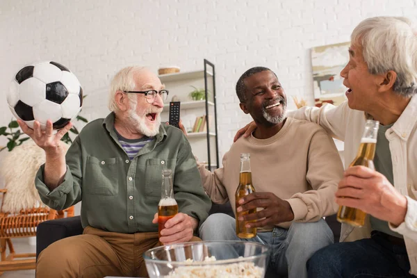 Positive interracial friends with beer and football spending time at home — Stock Photo