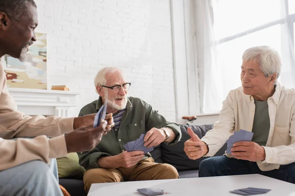 Ältere multiethnische Männer spielen Karten im Wohnzimmer — Stockfoto