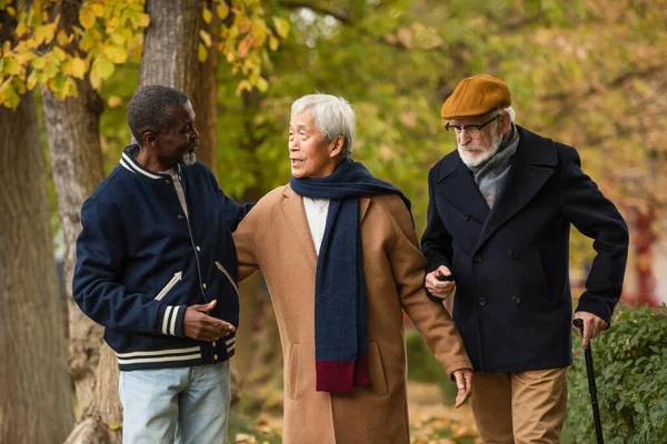 Hombre asiático hablando con viejos amigos multiétnicos en la calle urbana - foto de stock