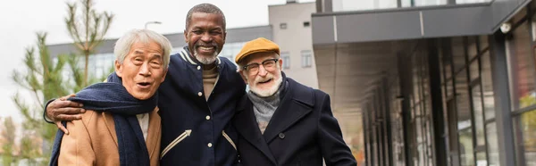 Alegre interracial amigos mirando a la cámara en la calle urbana, pancarta - foto de stock