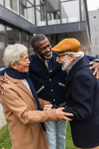 Smiling multiethnic men hugging on urban street — Stock Photo