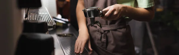 Cropped view of barista holding portafilter near coffee machine in cafe, banner — Stock Photo