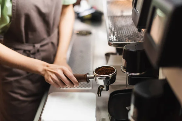 Ausgeschnittene Ansicht von Barista hält Portafilter in der Nähe von Schleifer in Café — Stockfoto