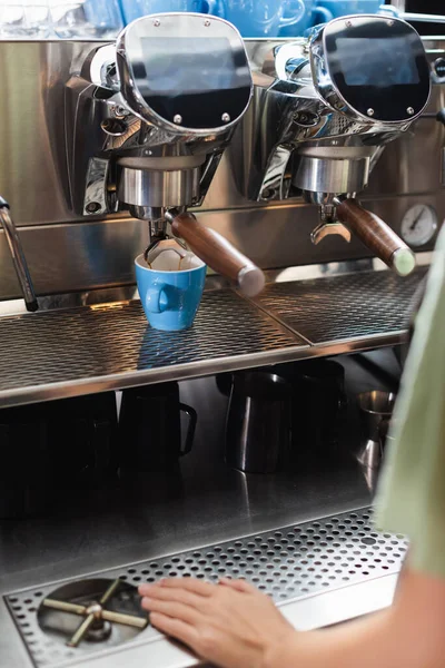 Cropped view of barista standing near cups and coffee machine in cafe — Stock Photo