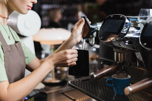 Vue recadrée du jeune barista travaillant avec la cruche à lait et la baguette à vapeur de la machine à café dans le café — Photo de stock