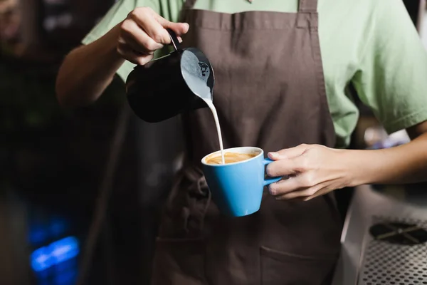 Ausgeschnittene Ansicht eines verschwommenen Barista, der im Café Milch in Kaffee gießt — Stockfoto