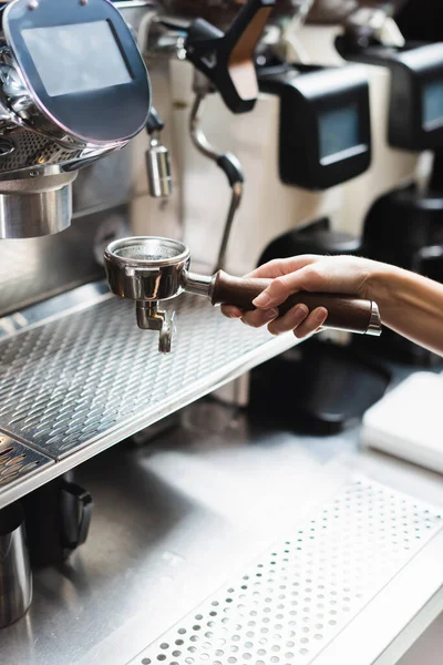 Обрезанный вид на бариста, держащего портативный фильтр возле кофеварки в кафе — стоковое фото