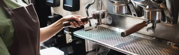 Cropped view of barista holding portafilter near coffee machine in restaurant, banner — Stock Photo