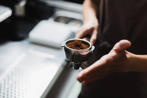 Vista ritagliata di barista offuscata che tiene portafilter con caffè in caffè — Foto stock