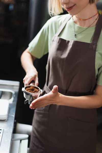 Cropped view of smiling barista holding portafilter with coffee in cafe — Stock Photo