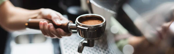 Cropped view of barista holding portafilter with fresh coffee in cafe, banner — Stock Photo