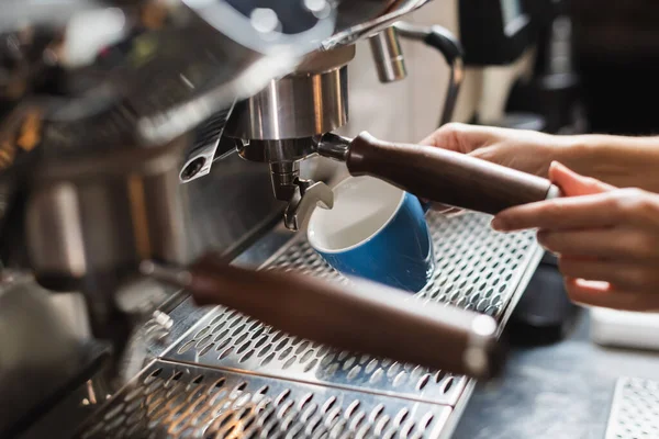 Cropped view of barista holding cup near coffee machine in cafe — Stock Photo