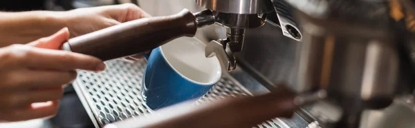 Vista recortada de la taza de celebración barista cerca de la máquina de café en la cafetería, pancarta - foto de stock