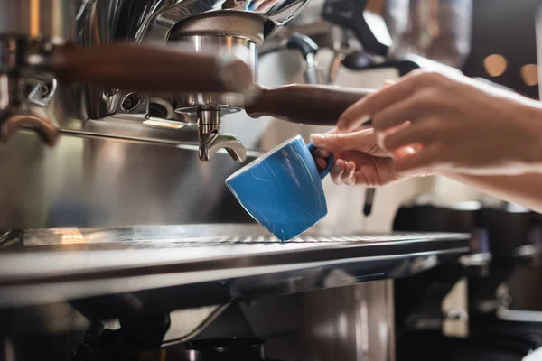 Vista cortada de barista segurando xícara perto portafilter de máquina de café no café — Fotografia de Stock