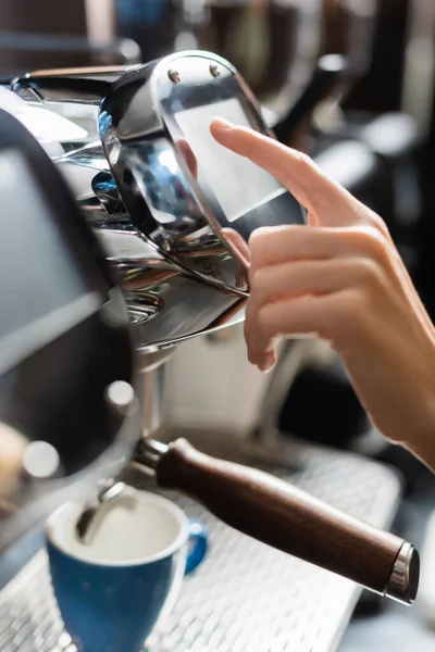 Vue recadrée de barista en utilisant une machine à café près de la tasse dans le café — Photo de stock