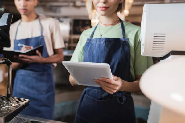 Vista ritagliata di barista utilizzando tablet digitale vicino alla macchina del caffè in caffè — Foto stock