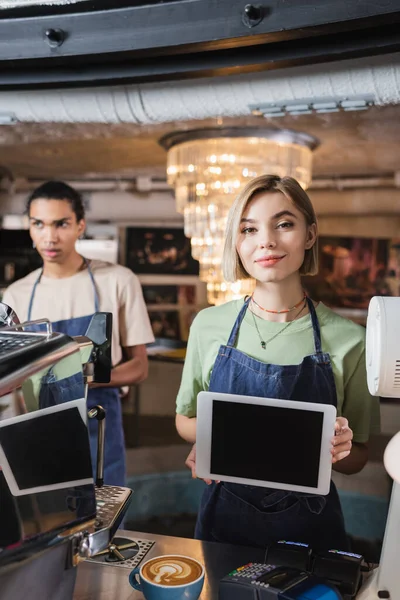 Barista sosteniendo tableta digital con pantalla en blanco cerca de la máquina de café y café en la cafetería - foto de stock