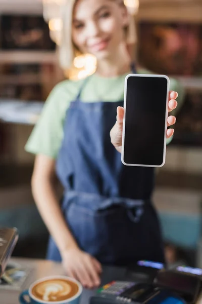 Smartphone with blank screen in hand of blurred barista in cafe — Stock Photo