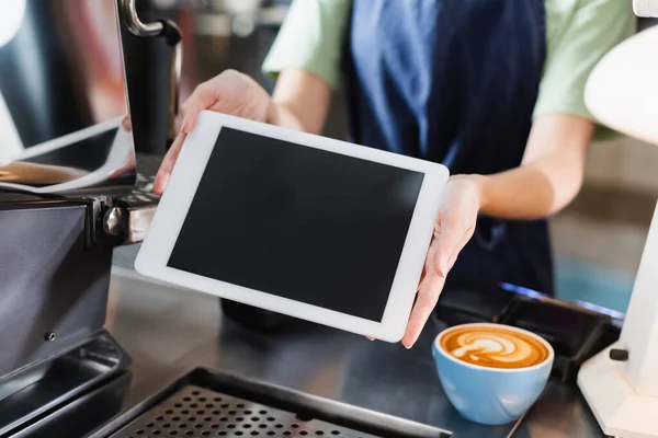 Обрезанный вид на бариста, держащего цифровой планшет с чистым экраном возле кофе в кафе — стоковое фото