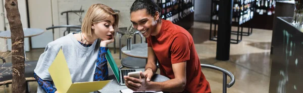 Positive interracial freelancers using smartphone in cafe, banner — Stock Photo