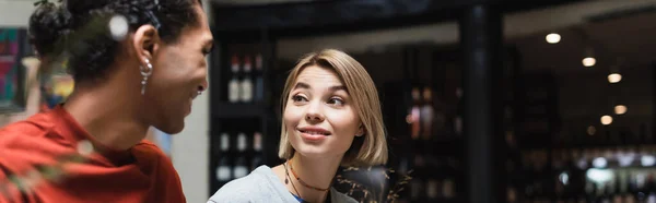 Smiling woman looking at african american boyfriend in cafe, banner — Stock Photo