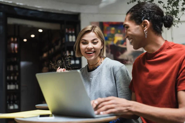 Positivo interrazziale freelance utilizzando il computer portatile in caffè — Foto stock