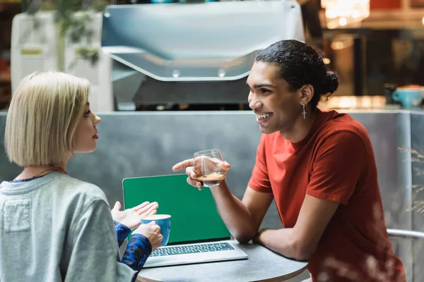 Smiling african american freelancer holding coffee near friend and colleague in cafe — Stock Photo