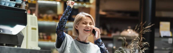 Захоплена блондинка розмовляє по смартфону в кафе, банер — стокове фото