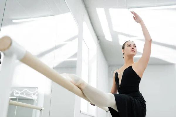 Low angle view of young dancer stretching in ballet studio — Stock Photo