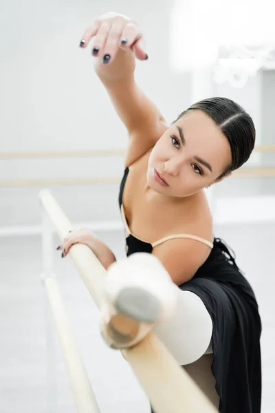 Mujer elegante estiramiento en la barra en el estudio de ballet — Stock Photo