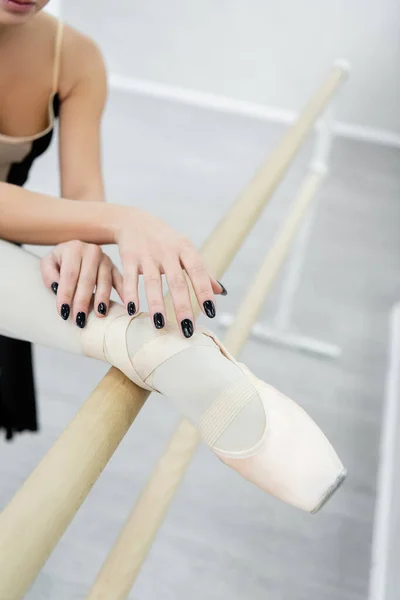 Vista cortada do bailarino de balé esticando a perna no barre no estúdio de dança — Fotografia de Stock