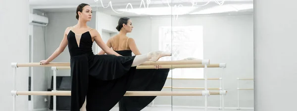 Bailarina jovem em vestido preto ensaiando perto de espelhos no estúdio, banner — Fotografia de Stock